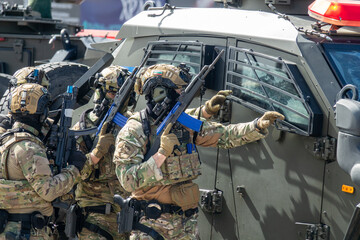 Fototapeta premium Armed Special Forces Soldiers in Camouflage Tactical Gear Storming Armored Vehicle During Military Training Exercise or Combat Operation
