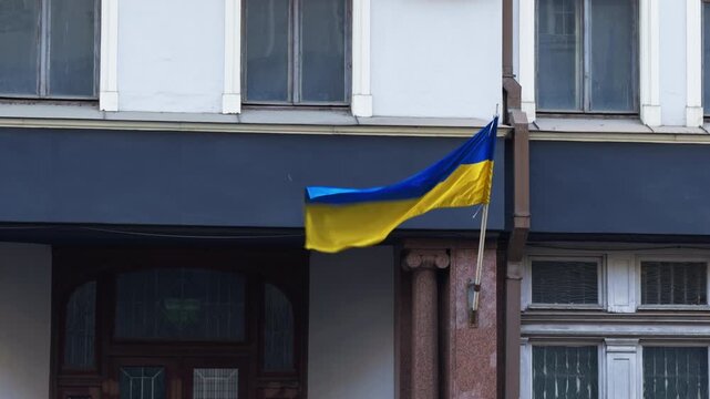 Brightly colored Ukrainian flag flying proudly on classical architecture in peaceful street setting
