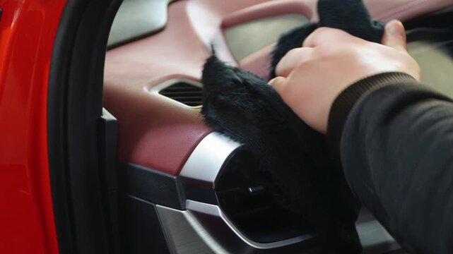 A man cleans the interior of a car using microfiber. Employees clean vehicle door professionally with microfiber for car polish. Man cleaning car interior. The detailing master clean the car interior.