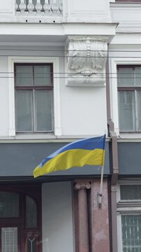 Building column displays flag rippling. Flag of Ukraine fluttering against historic architectural feature