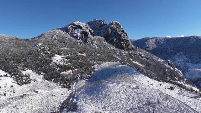 A smooth cinematic drone shot moving forward toward a fully snow-covered mountain peak. The landscape is filled with frost-covered trees and thick snow layers, creating a frozen winter atmosphere. Abo