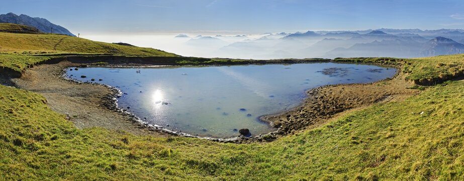 Small lake with the peaks of the Garda Mountains and Bergamo Alps, Monte Baldo, Malcesine, Verona Italy, Trentino-Alto Adige, Italy