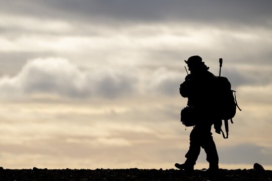Silhouette of a walking man with radio, rifle and backpack, Spitsbergen, Svalbard, Norway