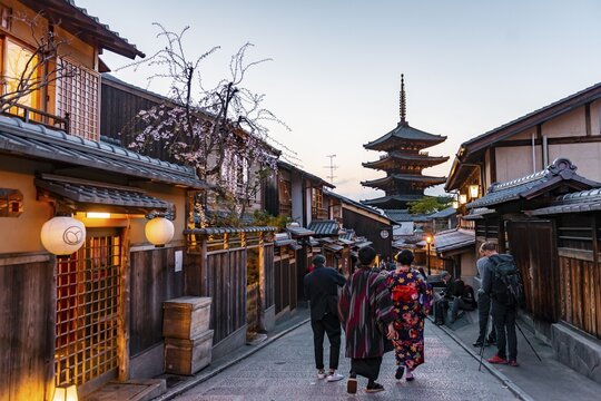 Pedestrian with kimono, Yasaka dori historical street in the Old Town with traditional Japanese houses, behind five-storey Yasaka pagoda of the Buddhist Hōkanji Temple, evening mood, Kyoto, Japan