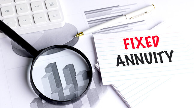 Fixed annuity concept with magnifier calculator pen and financial charts on desk guaranteed income 