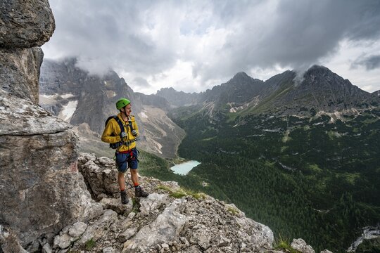 Young man, hiker with view of Lago di Sorapis and the peaks of Cime di Laudo and La Cesta, Via Ferrata Vandelli via ferrata, Sorapis circuit, Dolomites, Belluno, Italy