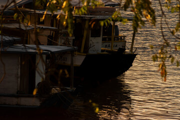 Obraz premium High quality tropical sunset landscape at Rio de Contas in Itacare Bahia Brazil featuring a boat crossing calm reflective waters with intense golden sunlight dramatic sky and realistic ocean reflectio