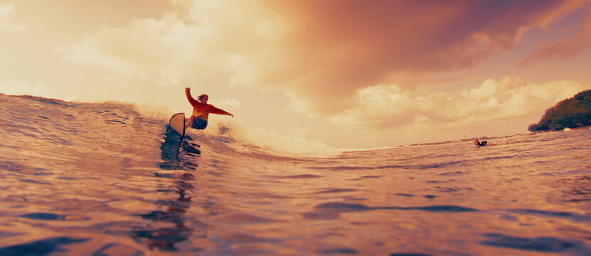 Surfer carving on a wave at sunset with warm golden light