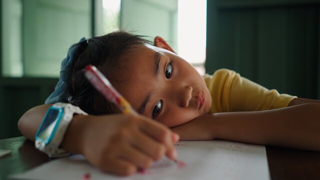 Young asian girl looking bored and tired while doing homework or studying at home
