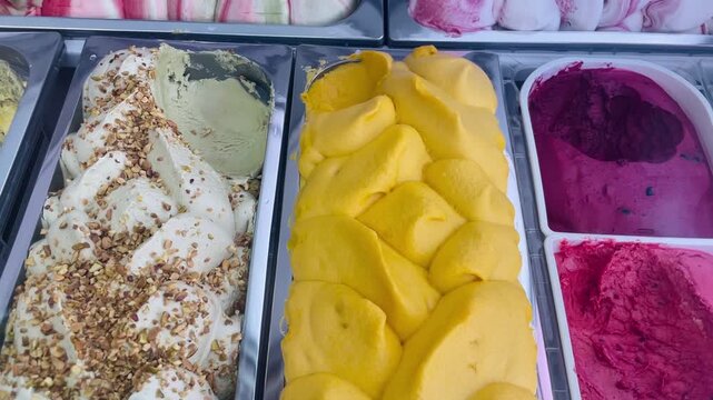 Colorful gelato display with mango pistachio berry sorbets bright yellow mango gelato, pistachio cream topped nuts, deep magenta