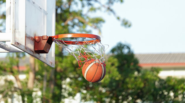Basketball swishing through the hoop and net on an outdoor court