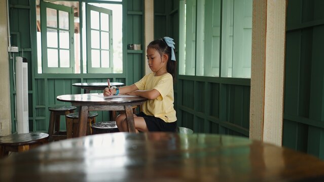 Asian girl concentrating on writing in a cafe, learning in a relaxed environment
