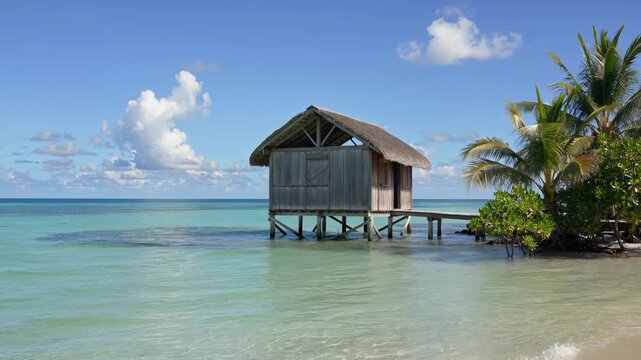 Traditional wooden hut on stilts over turquoise lagoon in French Polynesia