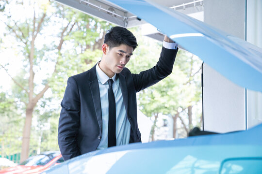Businessman Inspecting Car Engine Under Open Hood