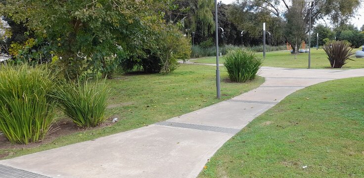 Sendero peatonal curvo en un parque urbano rodeado de &aacute;rboles y amplios espacios verdes, ideal para caminatas, paseos recreativos y actividades al aire libre en un entorno tranquilo y natural.