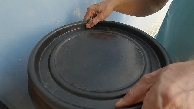 Close-up of a person pouring nitrogen-rich coffee grounds into a plastic compost bin for organic gardening.