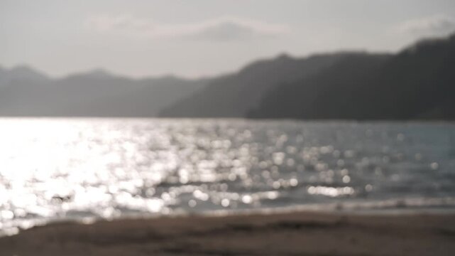 A sandbar at a river mouth flowing into a bay, with the silhouette of distant mountain ranges in the background