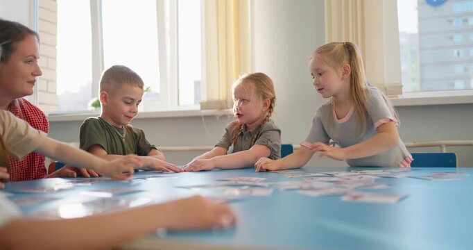 Preschool teacher guiding young children during an interactive classroom matching activity around a blue table in bright early learning room