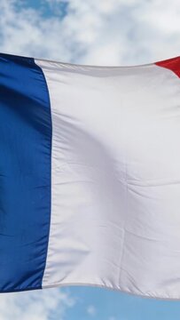 Vertical video: Flapping flag in wind under clouds, blue hoist and white field revealing red disc