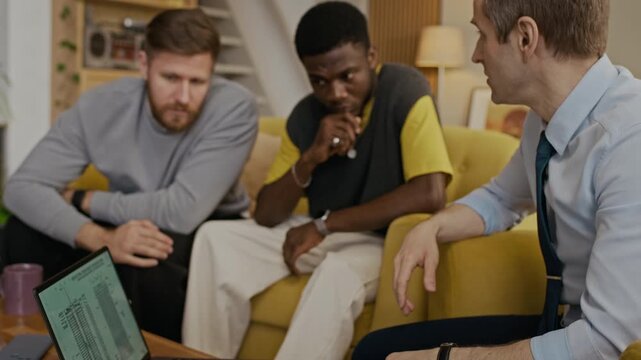 Handheld shot of Caucasian man communicating with best friends while resting on sofa, showing draft on laptop screen