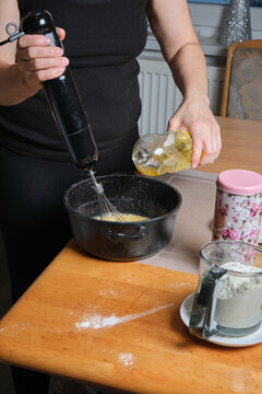 Pouring batter together. Mixing ingredients with motion. Cooking process involving pouring and mixing on wooden surface