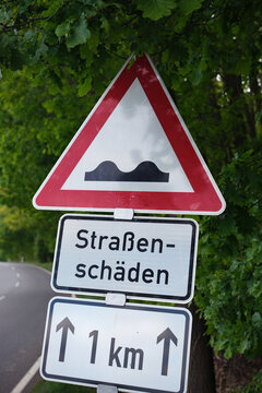 Verkehrszeichen Unebene Fahrbahn mit Zusatzschild Stra&szlig;ensch&auml;den auf 1 Kilometer. Deutschland