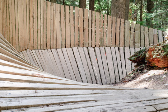 BC biking trail with wooden berm structure. Curved wood boardwalk with banked berm corner on advanced technical trail feature in North Vancouver, Canada rainforest. Selective focus.