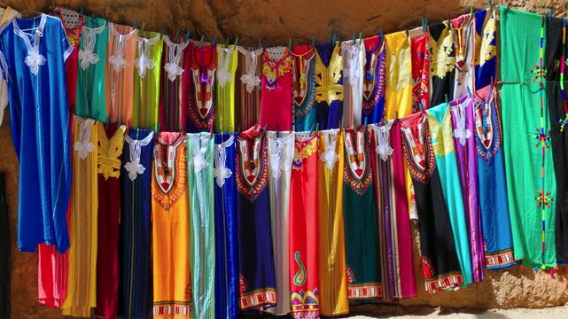 Close-up view of colorful traditional dresses and tunics displayed inside Todra Gorge.