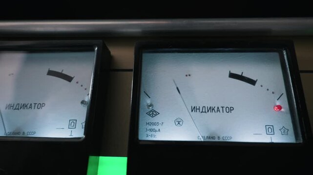 Vintage analog needle meter with Russian Indikator text monitors audio levels on a classic Soviet tube amplifier. A soft green light glows on the metal control panel.