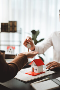 Real estate agent handing over house key to client, symbolizing home ownership, property investment, and successful mortgage agreement closing