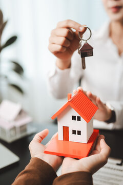 Real estate agent giving keys to new home owner, representing successful property acquisition, buying, investment, and profitable residential transaction