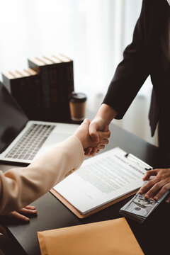 People shaking hands over contract agreement, negotiating a business deal with money on the table, representing concepts of success, partnership, corruption, and bribery