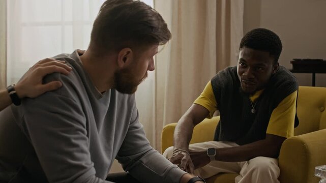 Medium shot of biracial best friends patting mans shoulder while trying to support him during life drama