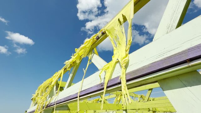 Frayed yellow fabric clings sadly to a weathered green frame, blowing gently in the wind. The empty, decaying seaside pavilion creates a hauntingly peaceful and nostalgic feeling.