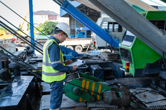 Engineer reviews a crane inspection checklist on a mobile crane deck, checking wire rope and hoist components to support safety, maintenance, and lifting readiness.