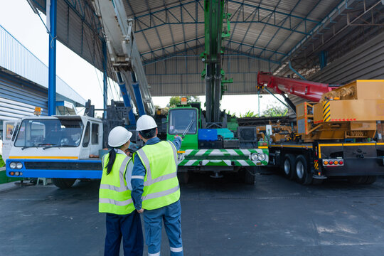 Engineers review mobile cranes in a maintenance shed during crane inspection, focusing on safety, equipment condition, lifting readiness, and worksite planning.