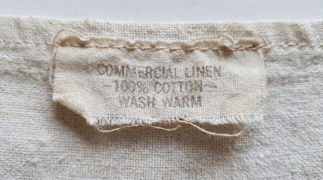 Close-up of a frayed fabric care label on textured cotton linen