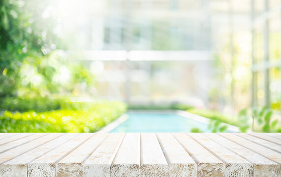Selective focus.Wood table top on garden with swimming pool background.For product placement design