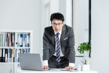 Naklejka premium Confident businessman working with laptop and documents in modern office