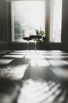Two glasses of red wine ready to drink. Cabernet Sauvignon in a glass, syrah or merlot in the stemware shining in sunlight on a living room coffee table for dinner. 