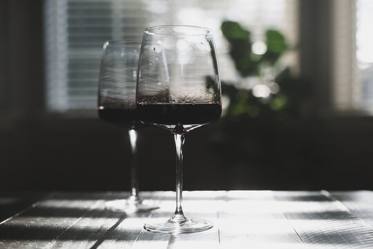 Two glasses of red wine ready to drink. Cabernet Sauvignon in a glass, syrah or merlot in the stemware shining in sunlight on a living room coffee table for dinner. 