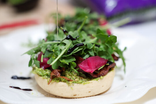 Fresh arugula lettuce and pickled radish on a vegan english muffin drizzled with olive oil. A healthy and delicious vegetarian lunch.