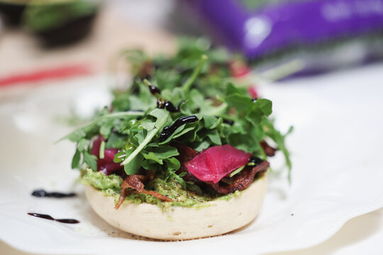 Fresh arugula lettuce and pickled radish on a vegan english muffin drizzled with olive oil. A healthy and delicious vegetarian lunch.