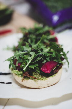 Fresh arugula lettuce and pickled radish on a vegan english muffin drizzled with olive oil. A healthy and delicious vegetarian lunch.