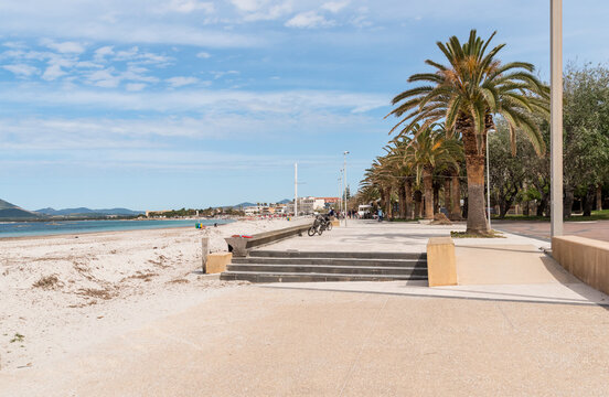 Alghero, Sardinia, Italy - May 7, 2026: The seafront promenade with tall palm trees and the beach of Lido di San Giovanni in Alghero. 