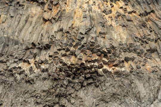 Basalt columns, natural pillars of hardened volcanic rock, famous for their geometric, often hexagonal shapes covered by moss on Reynisfjara, a wonderful black-sand beach found near Vik, Iceland