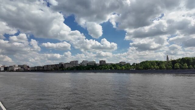 Russia. Moscow. May 16, 2026. View of Moskva River and Krasnoluzhsky railway bridge with moving passenger train near Luzhniki embankment under cloudy summer sky