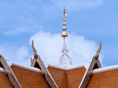 ntricate Buddhist temple architecture featuring orange terracotta tiles and golden finials against a blue sky.