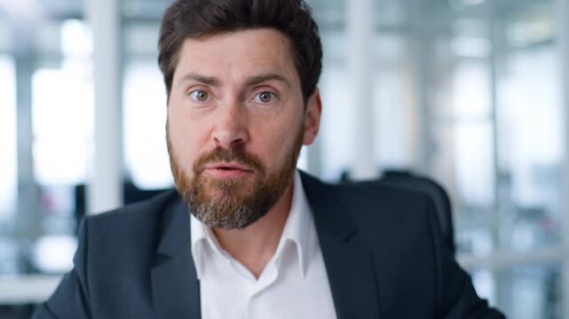 Close up negative angry Caucasian middle-aged business man talking with aggression looking at camera senior businessman mature male entrepreneur talk furious work problem working video call in office