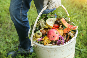 Farmer with food organic waste, scrap of vegetables and fruits with grass in bucket for compost closeup. Zero waste, composting concept © Viktor Iden